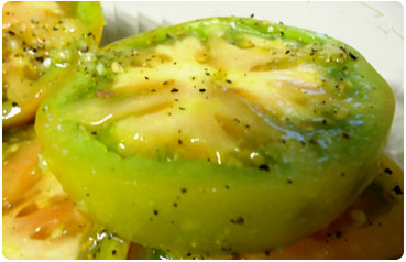 Green tomatoes marinading in olive oil and garlic for fried green tomatoes recipe by Maui Chef CJ.