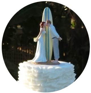 A bride and groom with surfboard cake topper at a Maui wedding.